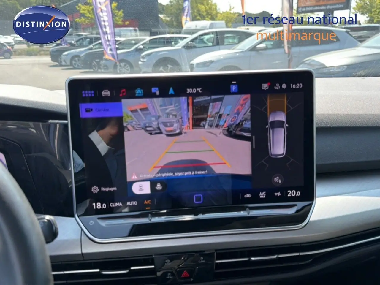 Vue intérieure du tableau de bord de la Volkswagen Golf SW 2026 avec écran tactile affichant la caméra de recul et l'aide au stationnement.