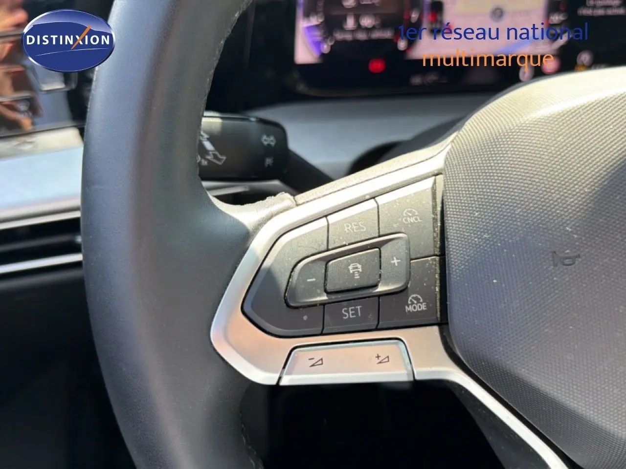 Gros plan sur les commandes au volant à gauche d’une Volkswagen Golf SW 2026, intérieur gris noir.