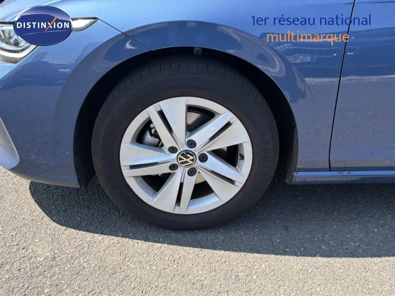 Gros plan sur la roue avant gauche d'une Volkswagen Golf SW bleu Anemone, avec jante alliage à cinq branches.