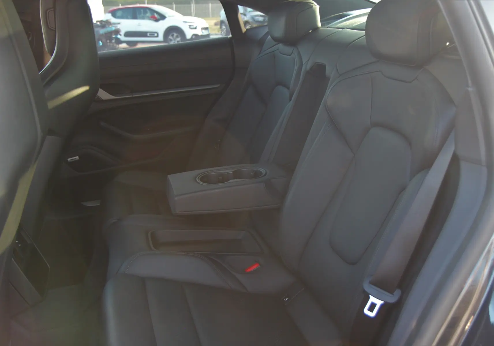 Vue intérieure arrière côté droit du Porsche Taycan Turbo 2020, montrant les sièges en cuir noir avec accoudoir central équipé de porte-gobelets.