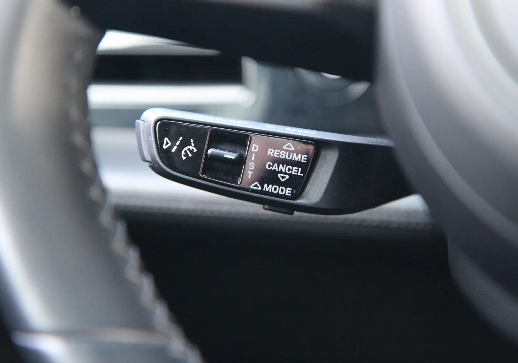 Gros plan sur la commande du régulateur de vitesse au volant d'une Porsche Taycan Turbo gris anthracite.