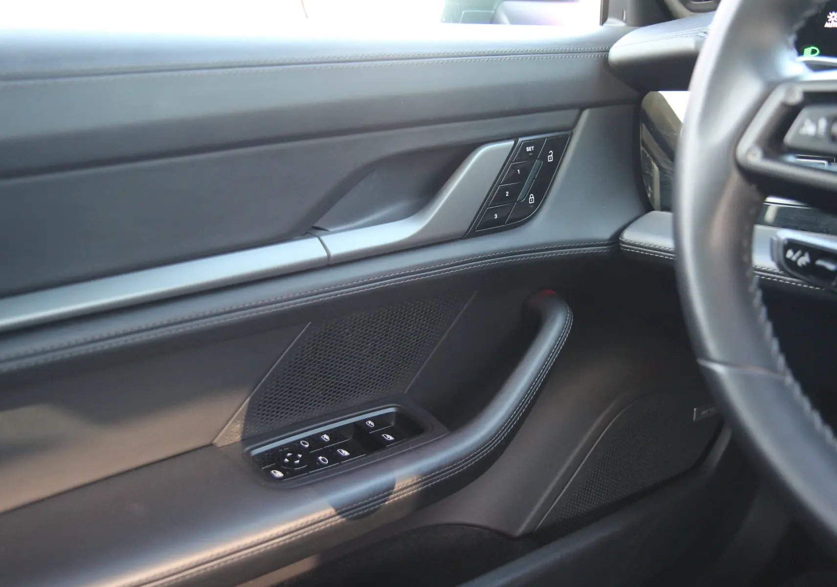 Détail de la porte côté conducteur du Porsche Taycan Turbo gris anthracite avec commandes de vitres et verrouillage.