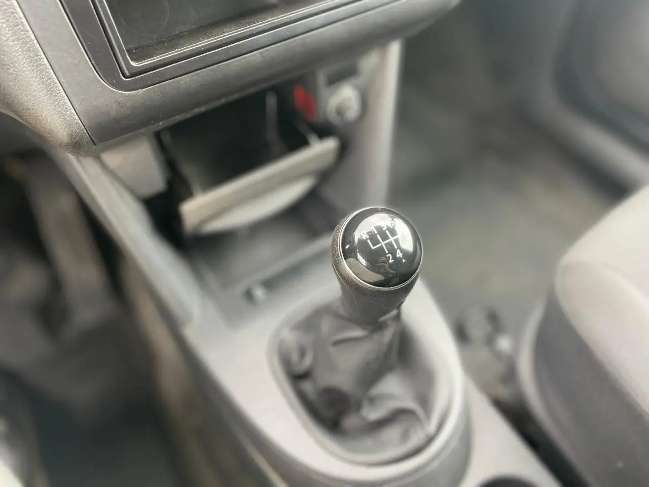 Le levier de vitesses manuel en gros plan dans l'habitacle du Volkswagen Caddy blanc, avec console centrale visible floue.