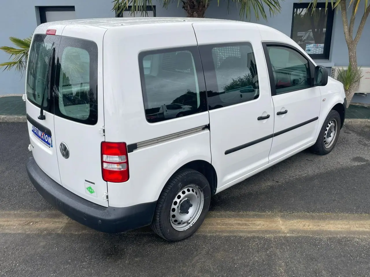 Volkswagen Caddy blanc Candy vue 3/4 arrière droit avec galerie de toit et vitres teintées.