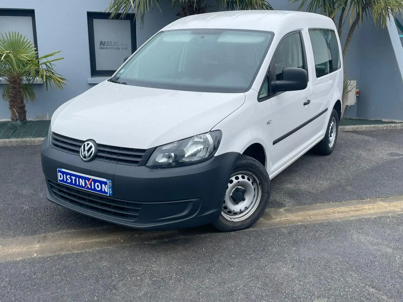 Volkswagen Caddy blanc Candy en 3/4 avant droit, avec pare-chocs noir et jantes acier simples.