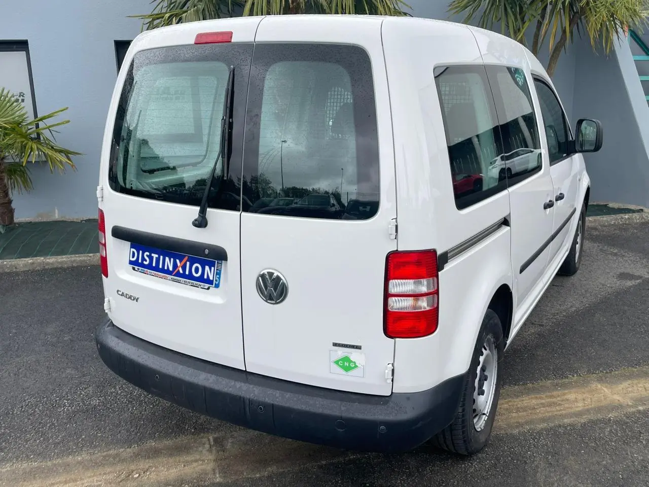 Vue 3/4 arrière droite d'un Volkswagen Caddy blanc Candy Van 2.0i Ecofuel avec galerie de toit et badge CNG.