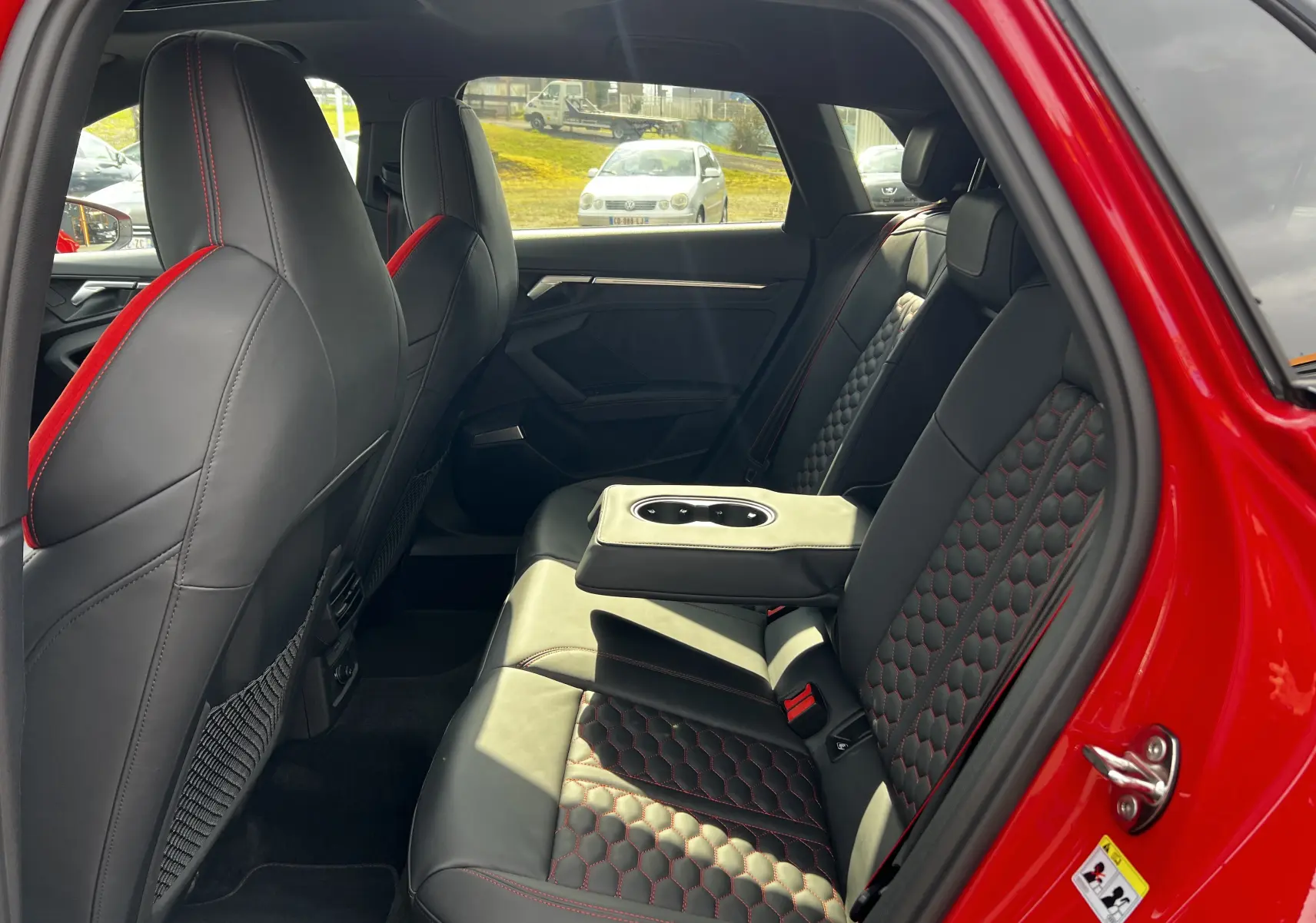 Vue intérieure arrière droite de l'Audi RS3 Sportback rouge 2022 avec sièges cuir noir à surpiqûres rouges et accoudoir central.