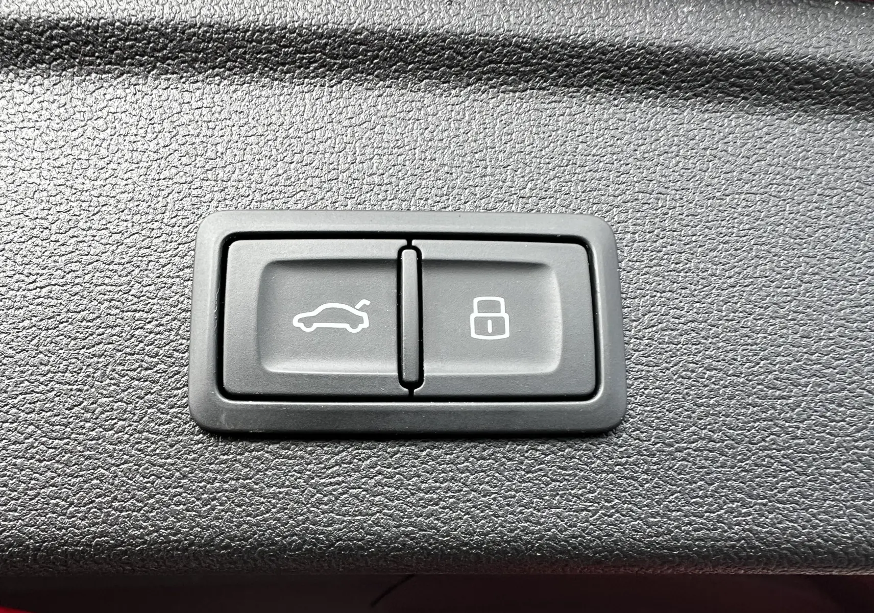 Boutons de commande pour ouverture du coffre et verrouillage, situés sur la garniture intérieure d'une Audi RS3 Sportback rouge 2022.