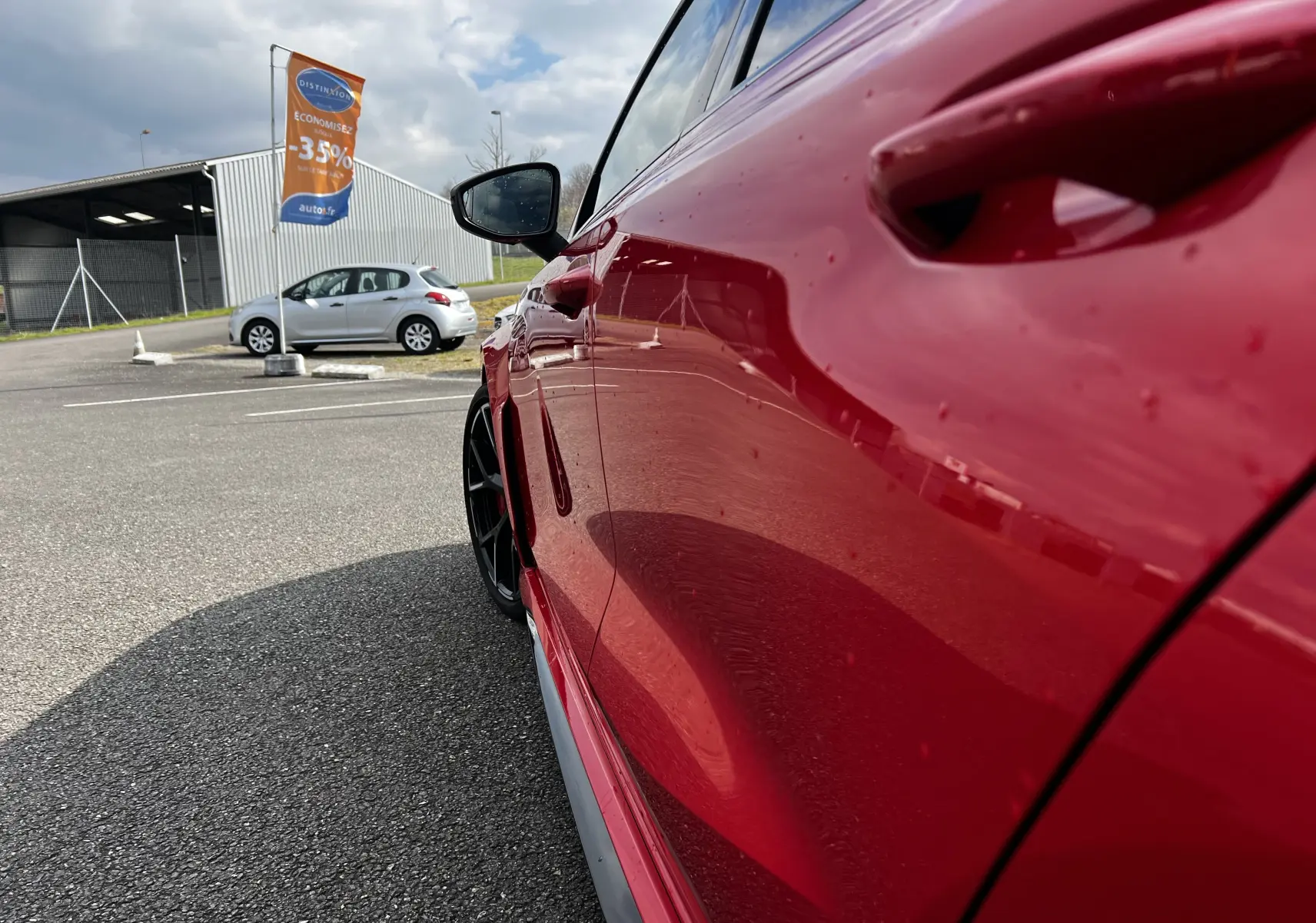 Vue rapprochée du côté gauche de l'Audi RS3 Sportback rouge 2022, mettant en valeur la portière et la jante noire.