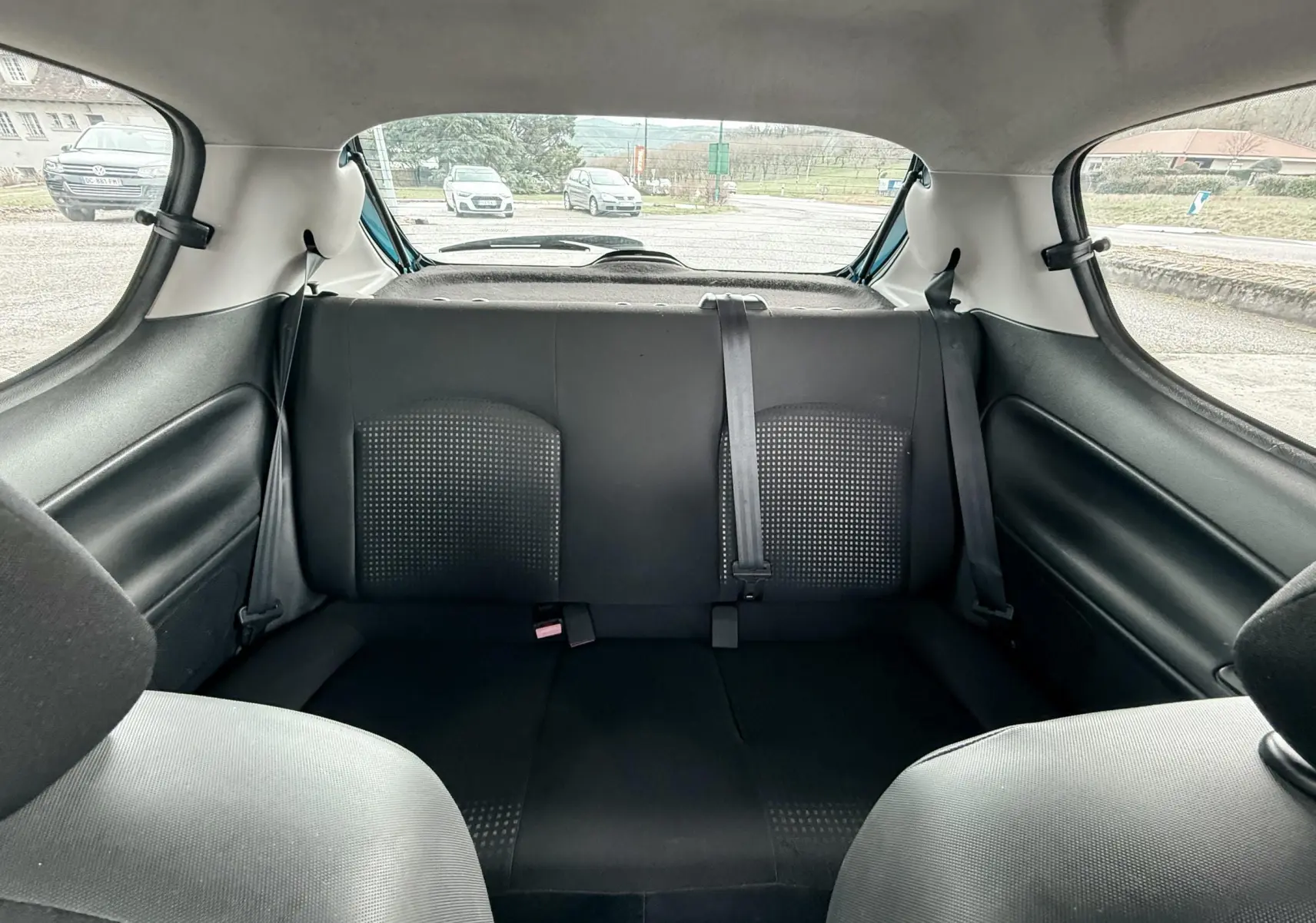 Vue intérieure arrière montrant la banquette arrière noire en tissu de la Peugeot 206+ bleue 3 portes.