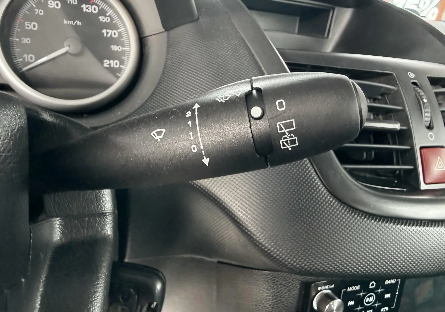 Gros plan sur la commande d’essuie-glace noire et le tableau de bord noir de la Peugeot 206+ 1.1 i 60.