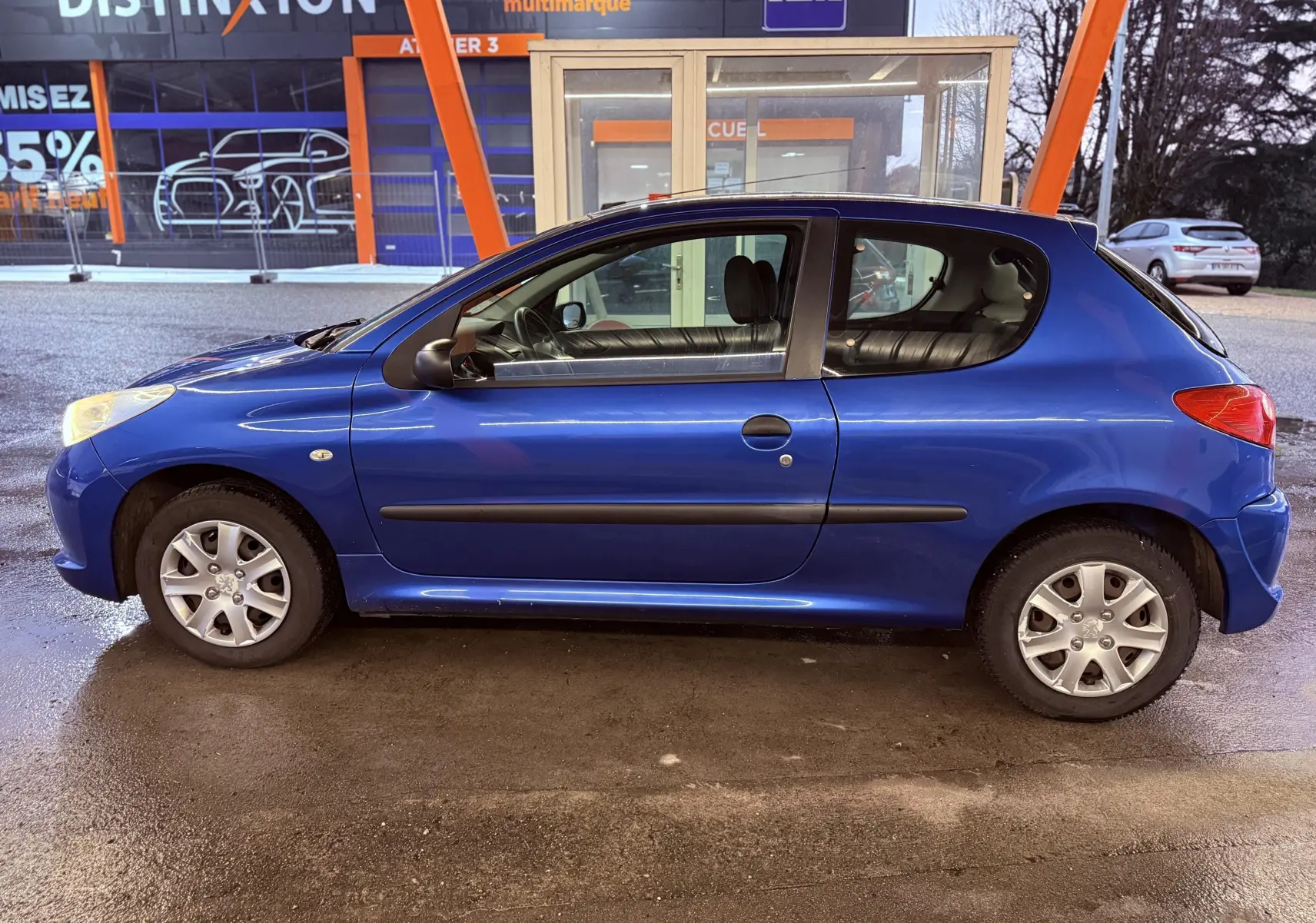 Profil latéral droit d'une Peugeot 206+ bleue à trois portes, avec poignées et protections noires visibles.