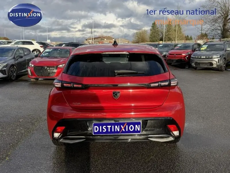 Vue arrière d'une Peugeot 308 2024 rouge Elixir, mettant en valeur ses feux arrière étirés et son logo central noir.
