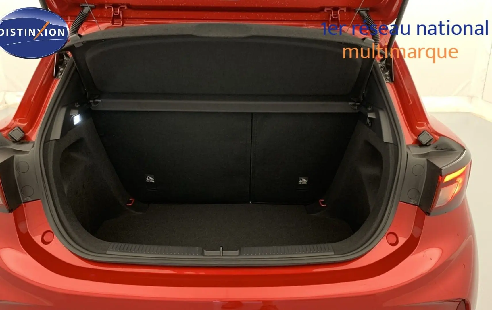 Coffre ouvert vu de l’arrière d’une MG3 1.5 L Hybrid+ 195 ch Luxury en rouge Diamond Red avec intérieur noir.
