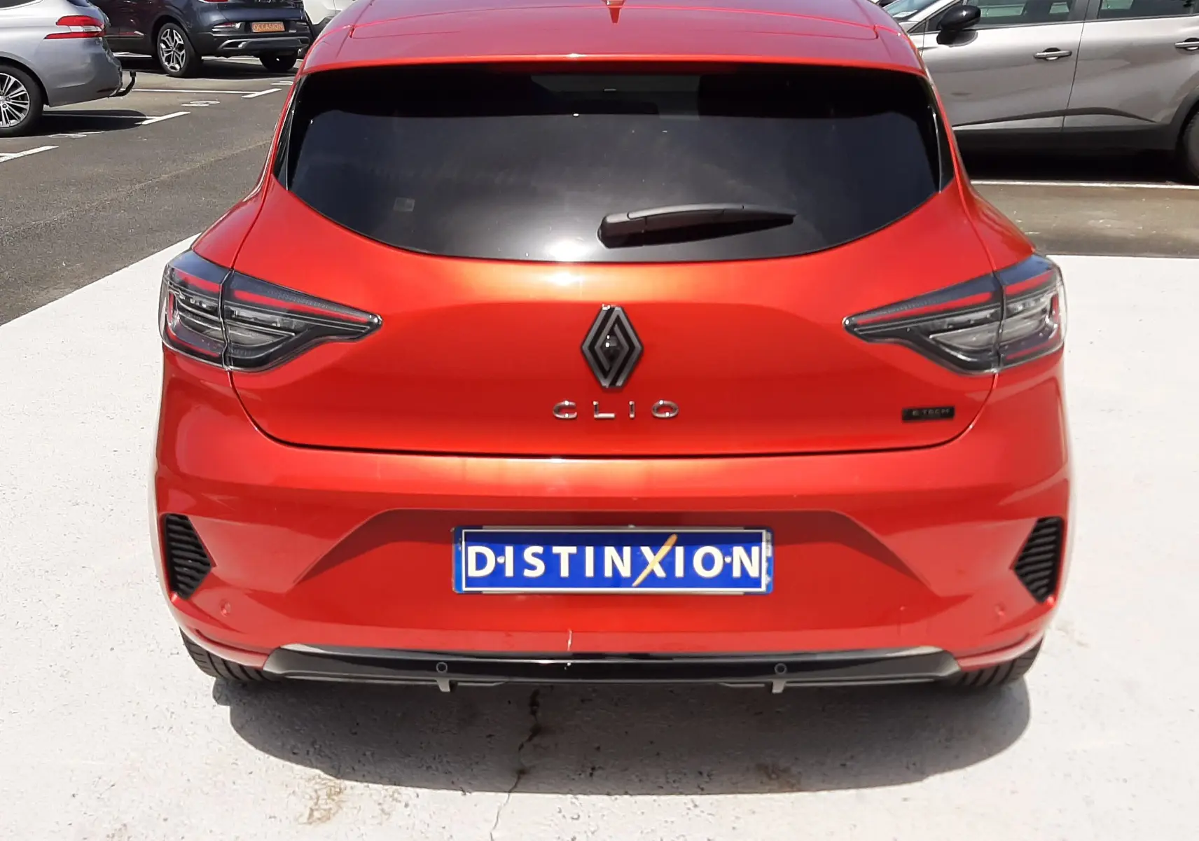 Vue arrière d'une Renault Clio V rouge flamme métal, avec feux arrière LED et vitre arrière teintée.