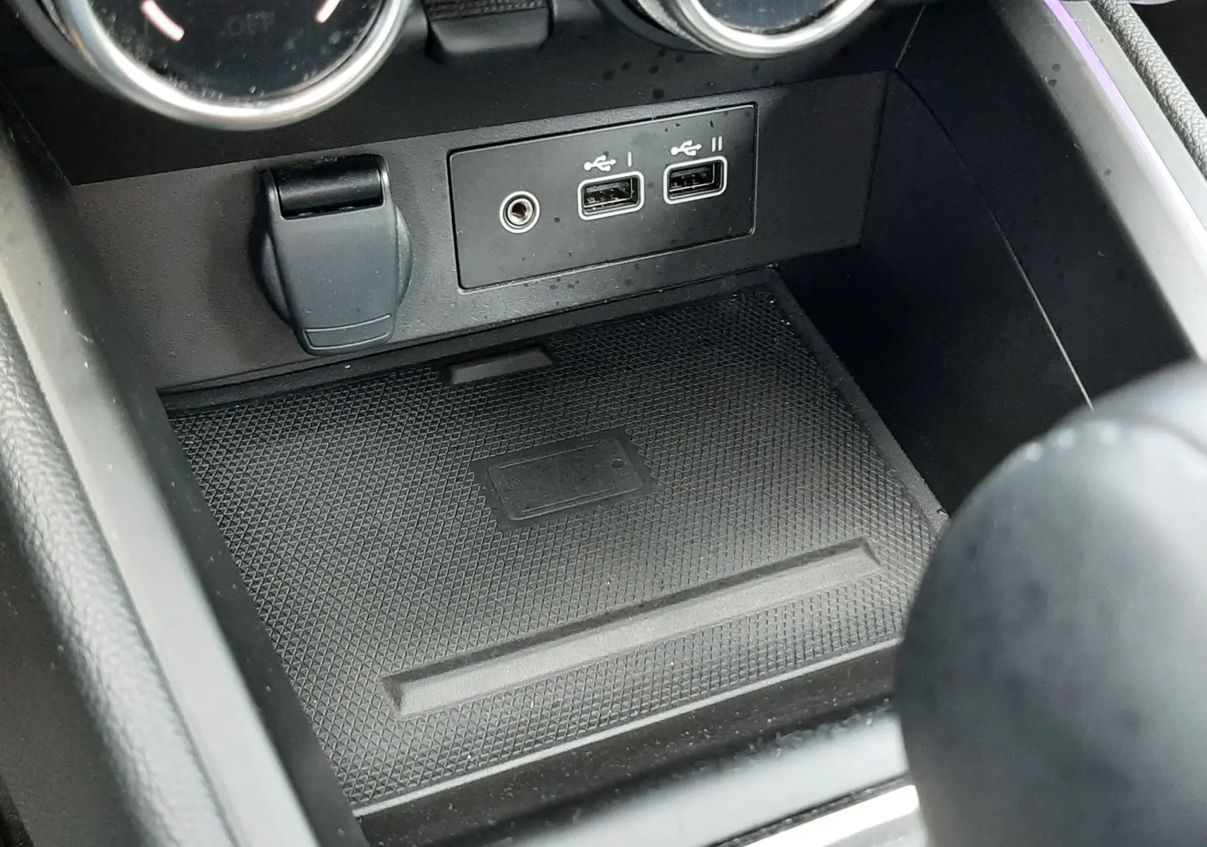 Vue rapprochée de la console centrale de la Renault Clio V rouge flamme, montrant les ports USB et commandes de climatisation.