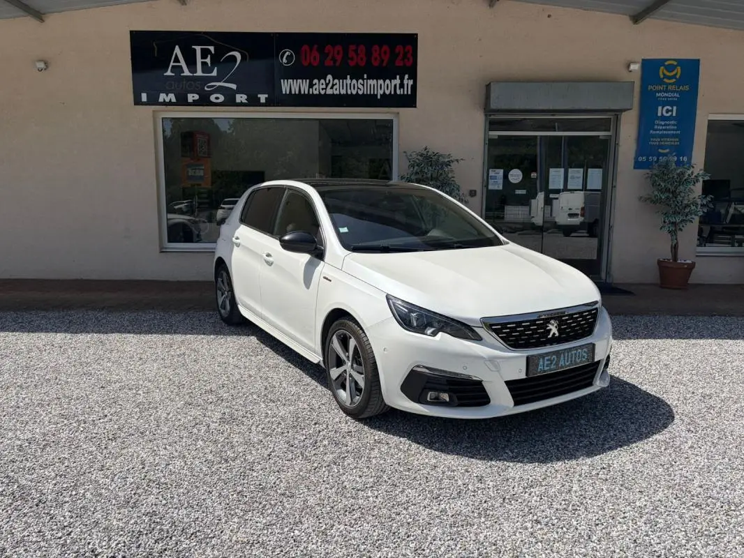 Peugeot 308 GT-Line blanche vue en 3/4 avant droit, avec jantes alliage et calandre noire distinctive.