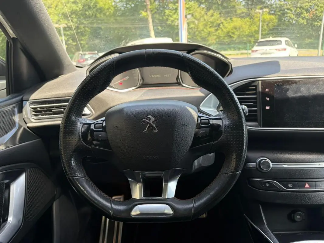 Vue intérieure centrée sur le volant noir perforé de la Peugeot 308 GT-Line 2017 avec tableau de bord et écran tactile.