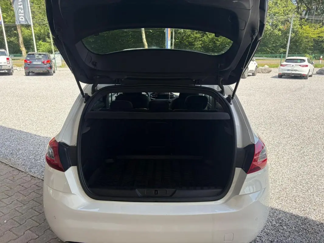 Vue arrière d'une Peugeot 308 GT-Line blanche de 2017 avec le coffre ouvert, montrant l'espace de chargement vide.