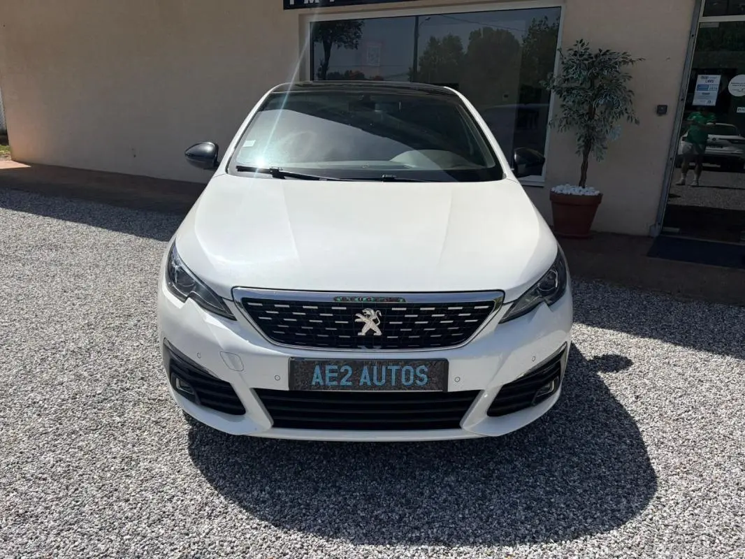 Vue frontale d’une Peugeot 308 GT-Line blanche de 2017, avec calandre noire et logo lion distinctif.