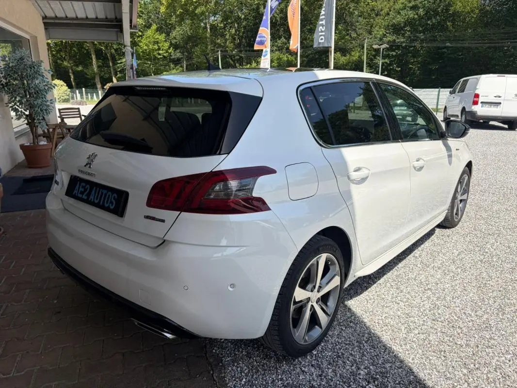 Peugeot 308 GT-Line blanc vue 3/4 arrière droit, avec jantes alliage et vitres teintées, stationnée en extérieur.