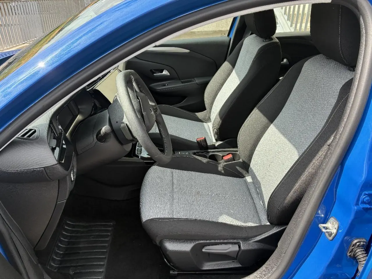 Vue intérieure côté conducteur de l’Opel Corsa 2025 bleu, montrant sièges bi-tons gris et noir et volant multifonction.