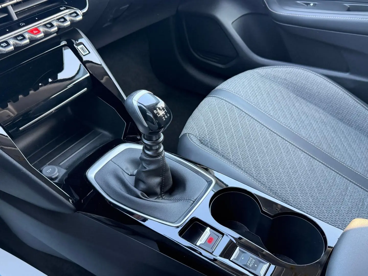 Vue rapprochée de la console centrale de la Peugeot 208 gris Artense, avec levier de vitesse manuel et siège tissu gris.