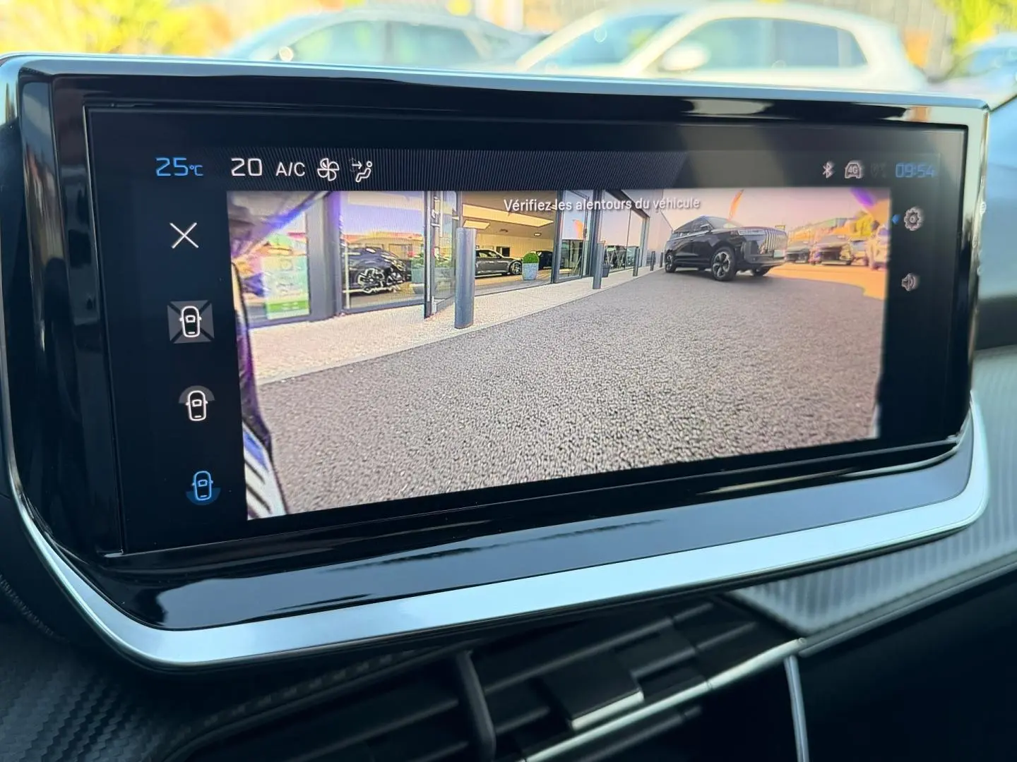 Écran tactile intérieur montrant la caméra de recul avec vue sur un SUV noir en extérieur, jour ensoleillé.