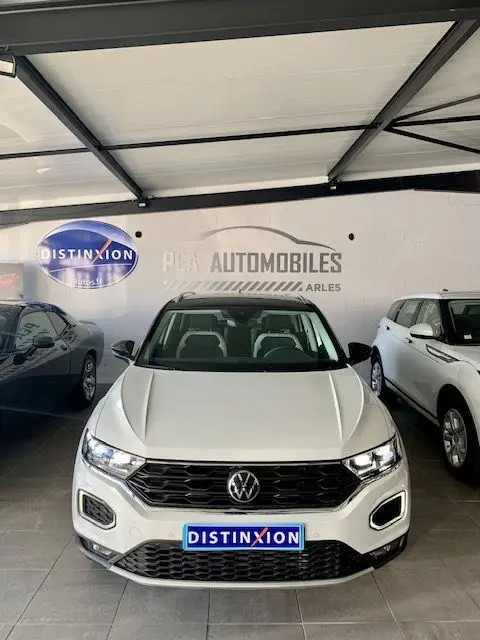 Volkswagen T-Roc blanc vue de face en intérieur, avec calandre noire et phares LED allumés.