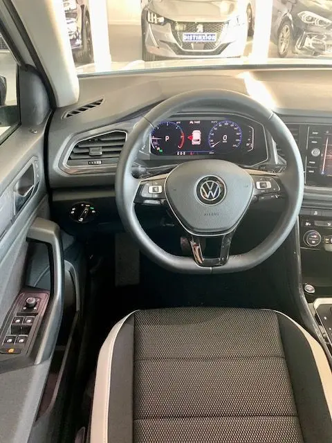 Vue intérieure du Volkswagen T-Roc 2021 montrant le volant cuir noir avec commandes et tableau de bord numérique.
