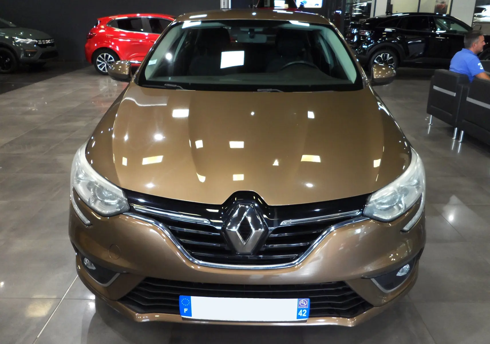 Vue frontale d'une Renault Mégane IV TCe 100 CH LIFE brun cappuccino, mettant en valeur sa calandre chromée et ses phares modernes.