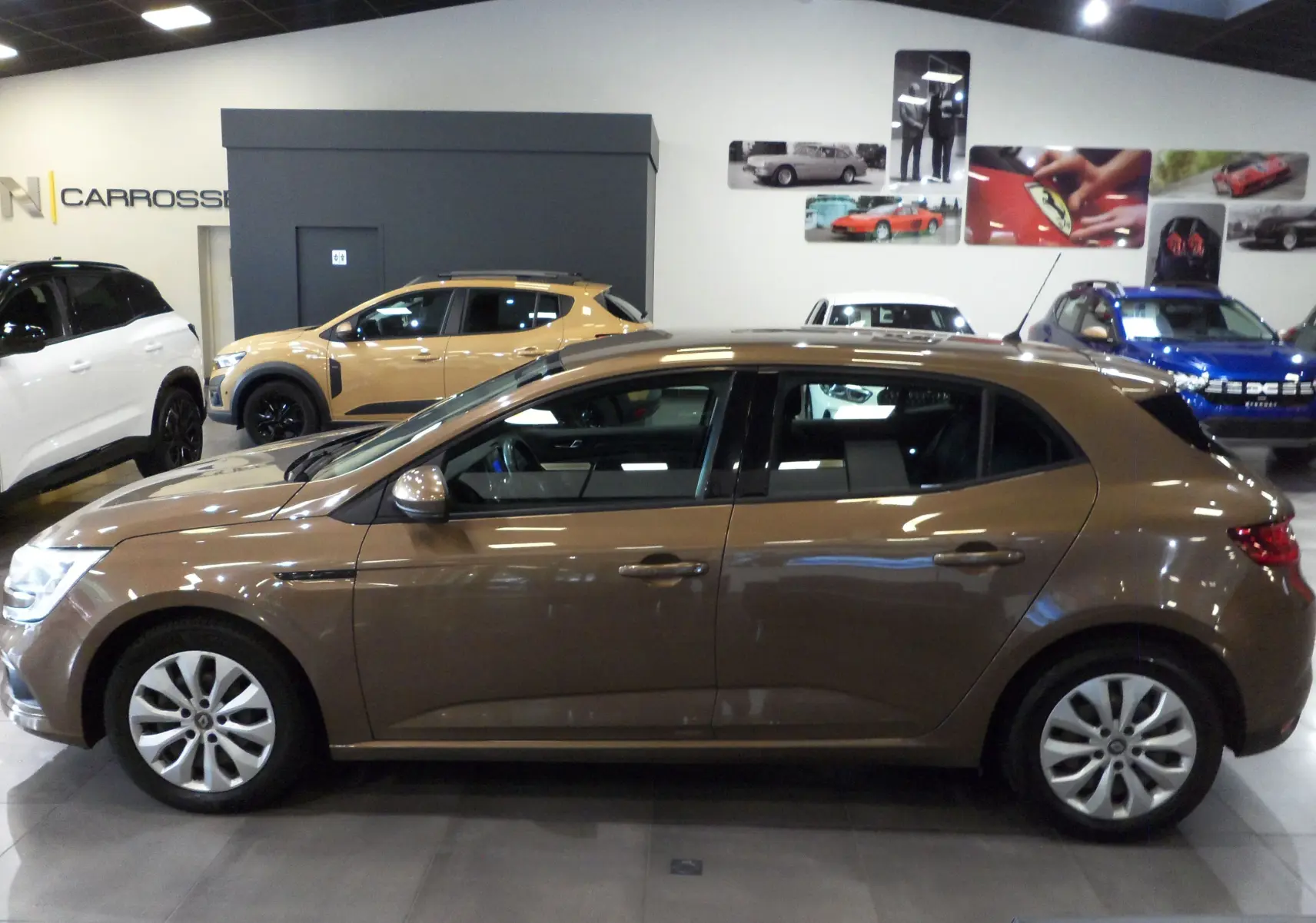 Profil côté gauche d'une Renault Mégane IV TCe 100 Life brun capuccino en intérieur, avec jantes alliage et lignes épurées.