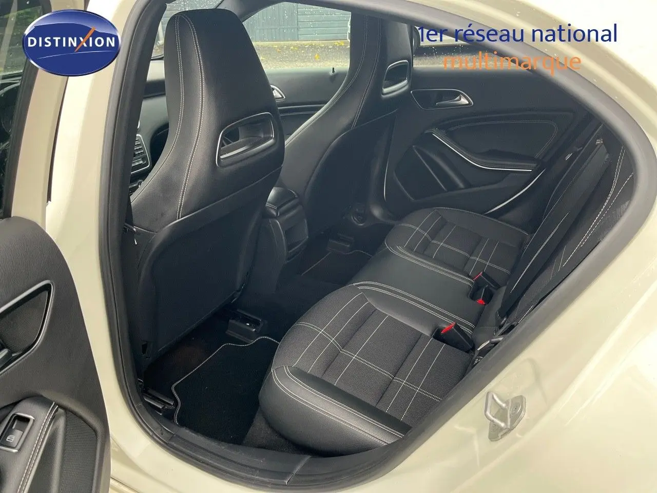 Vue intérieure arrière côté droit d'une Mercedes Classe A 180 Sensation blanche de 2013 avec sièges tissu noir à surpiqûres blanches.