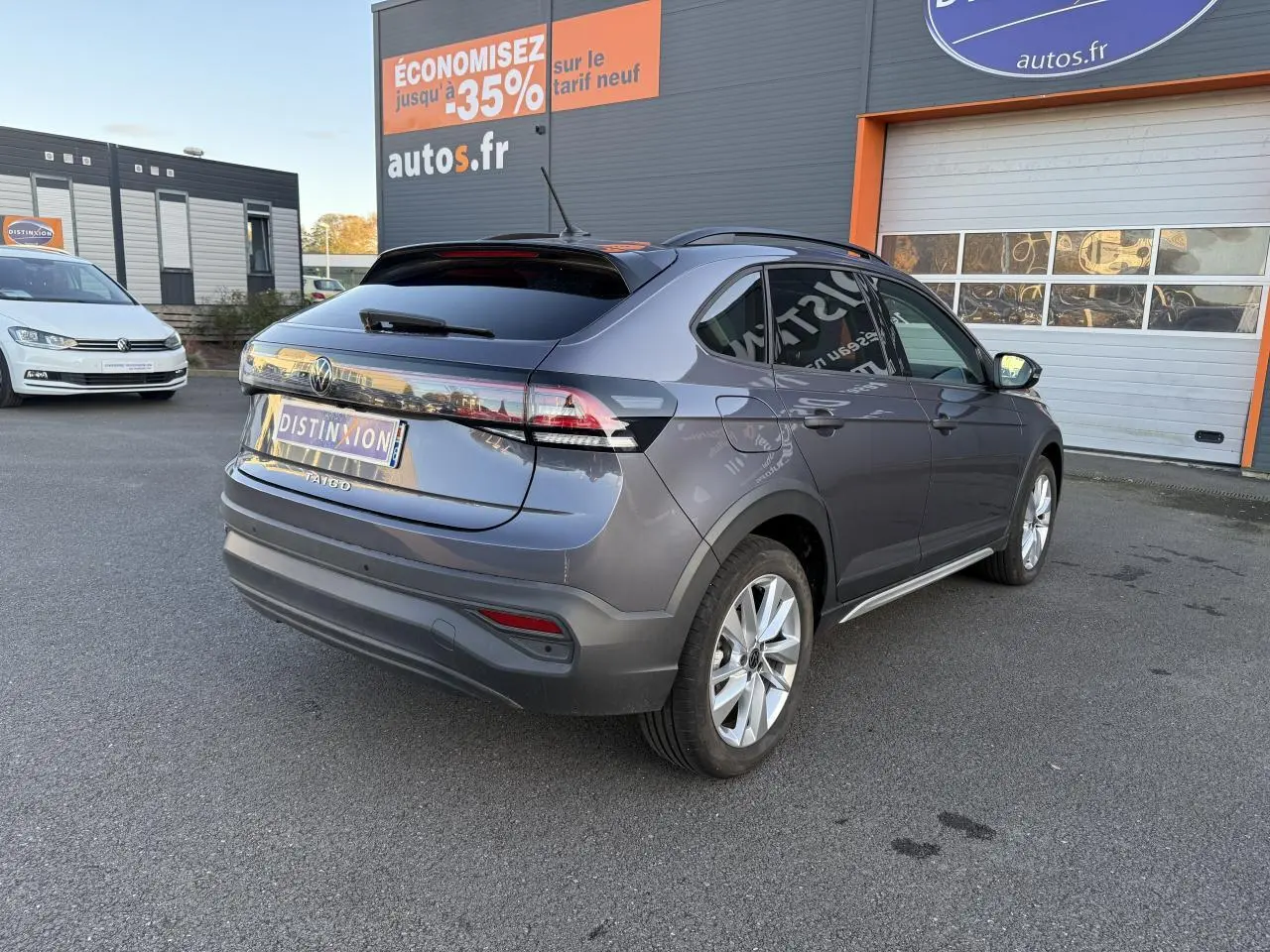 Vue 3/4 arrière droite d'un Volkswagen Taigo gris INC avec jantes alliage et vitres arrière surteintées.