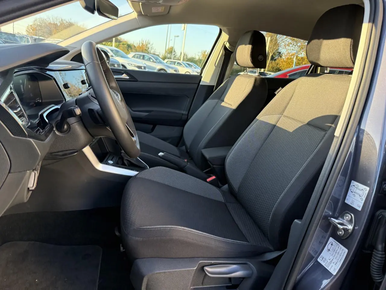 Vue intérieure côté conducteur du Volkswagen Taigo 2025 gris INC, montrant sièges avant et tableau de bord moderne.