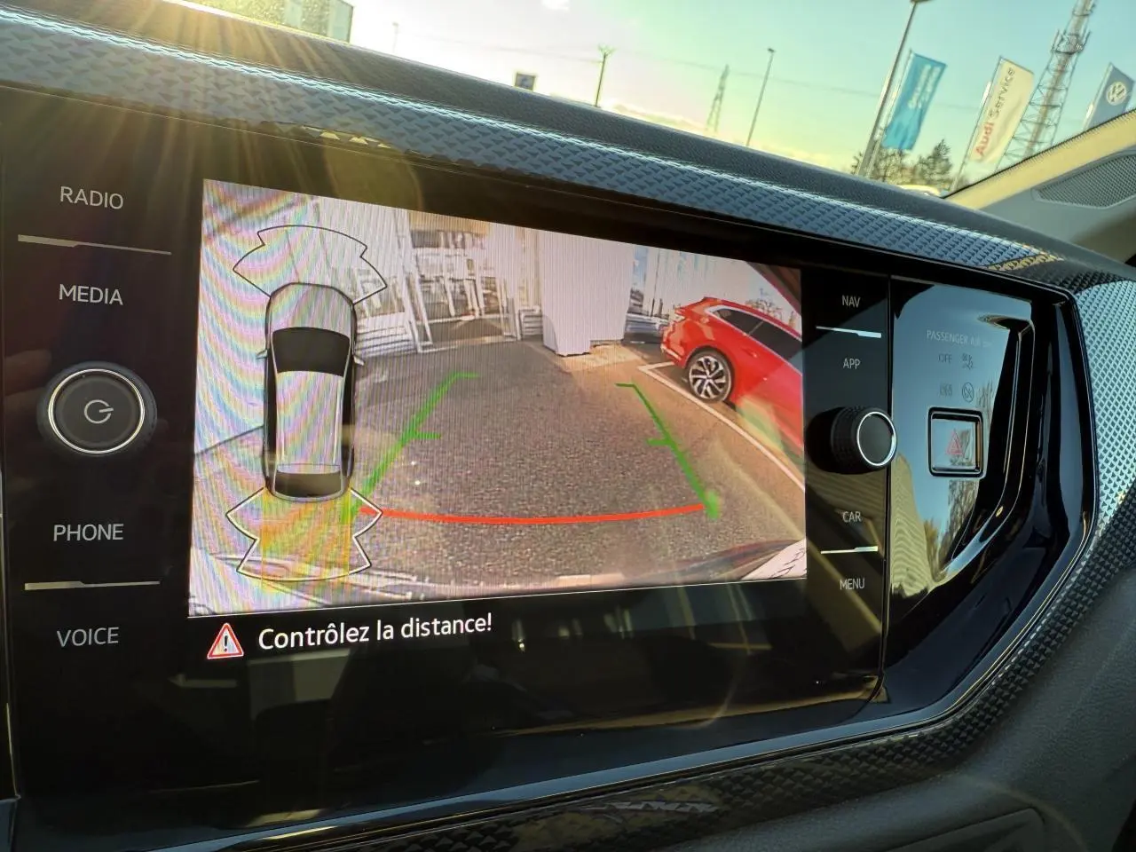 Écran de caméra de recul dans un Volkswagen Taigo 2025, vue arrière avec véhicule rouge à droite.