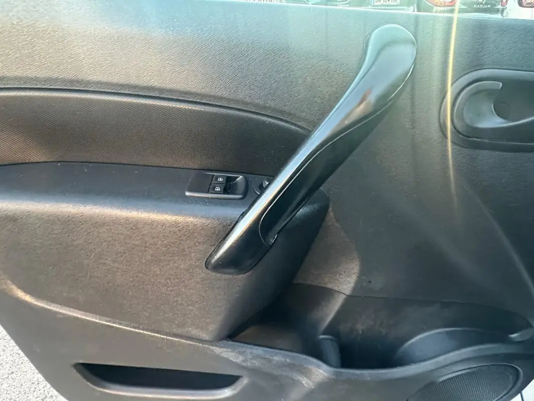 Gros plan sur la poignée intérieure noire de la porte côté gauche du Renault Kangoo Express blanc 2020.