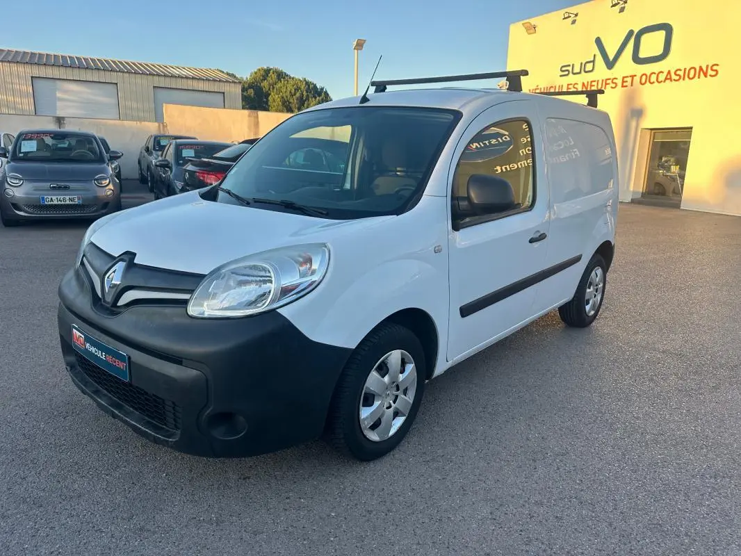 Renault Kangoo Express blanc en 3/4 avant droit, avec pare-chocs noir et porte latérale visible, stationné en extérieur.
