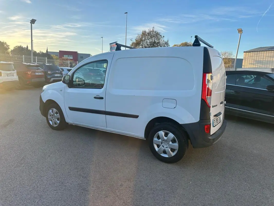 Renault Kangoo Express blanc vu de côté gauche en 3/4 arrière, avec porte latérale et barres de toit noires.