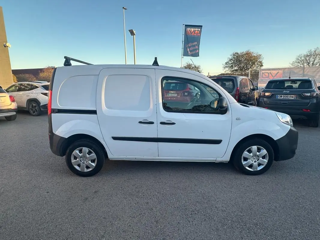 Renault Kangoo Express blanc vu de profil côté gauche, fourgonnette utilitaire avec porte latérale et barres de toit.