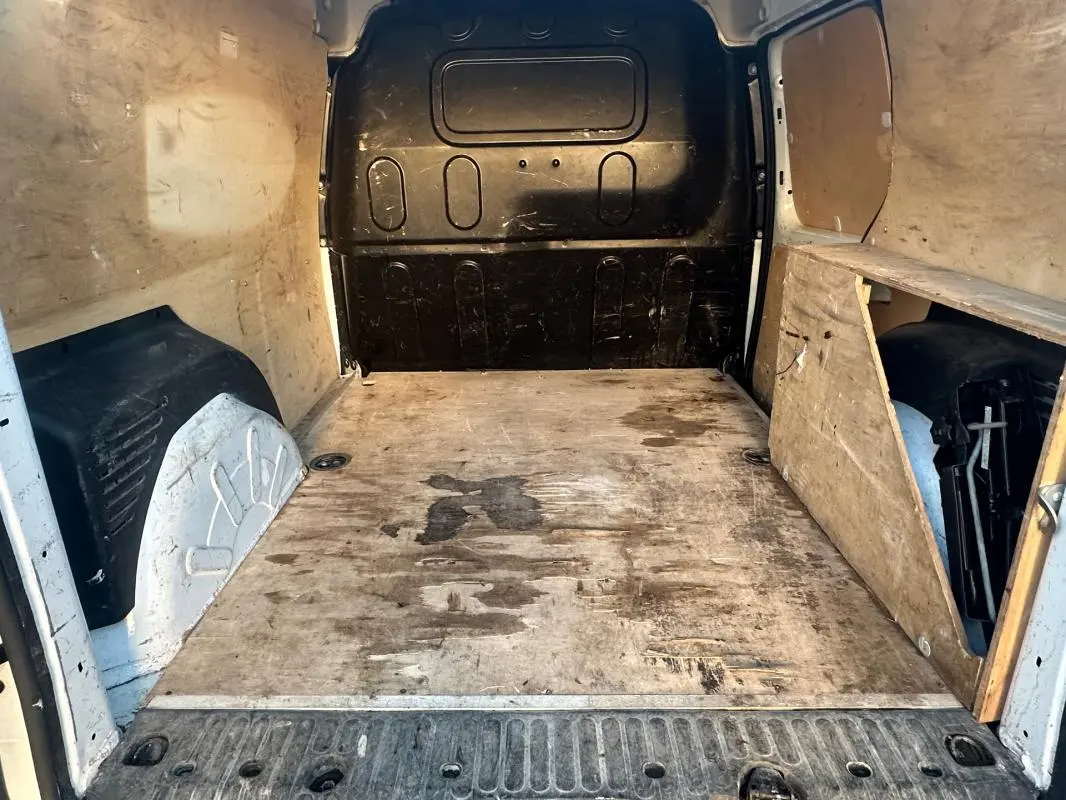 Vue intérieure arrière du Renault Kangoo Express blanc 2020, montrant la zone de chargement en bois usé et les parois latérales.