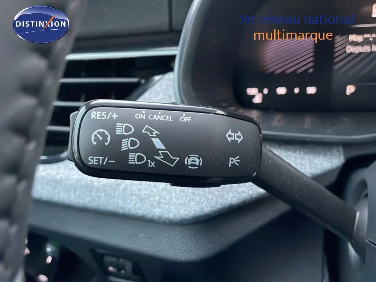 Gros plan sur le commodo de régulateur de vitesse du Skoda Kamiq gris graphite, avec tableau de bord flou en arrière-plan.