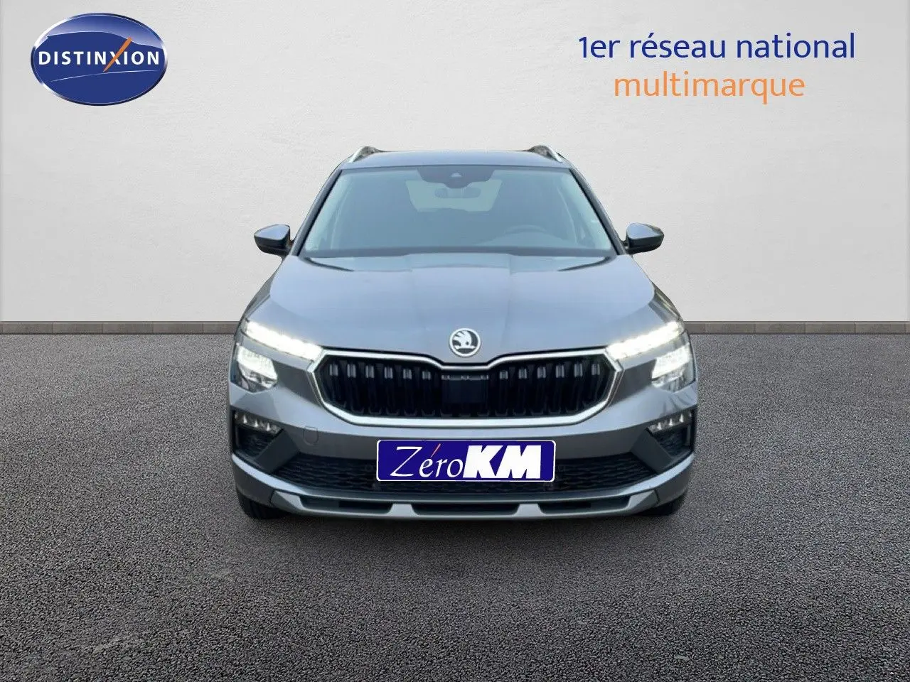 Vue frontale d'un Skoda Kamiq gris graphite métal 2025 avec feux LED allumés et calandre noire distinctive.