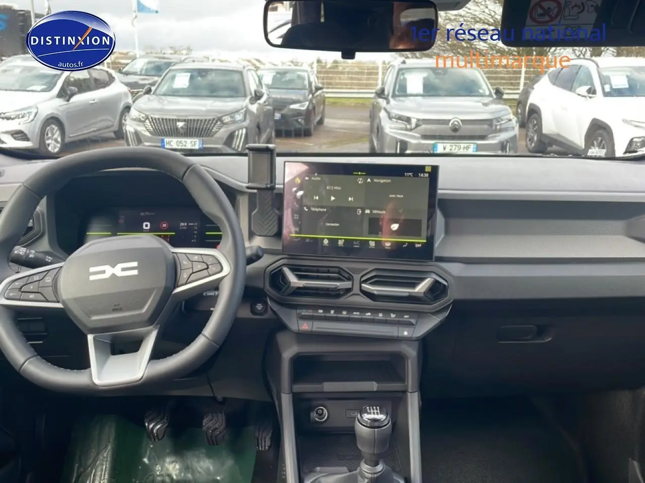 Vue intérieure du tableau de bord du Dacia Duster 2026 vert cèdre, avec volant multifonction et écran tactile central.