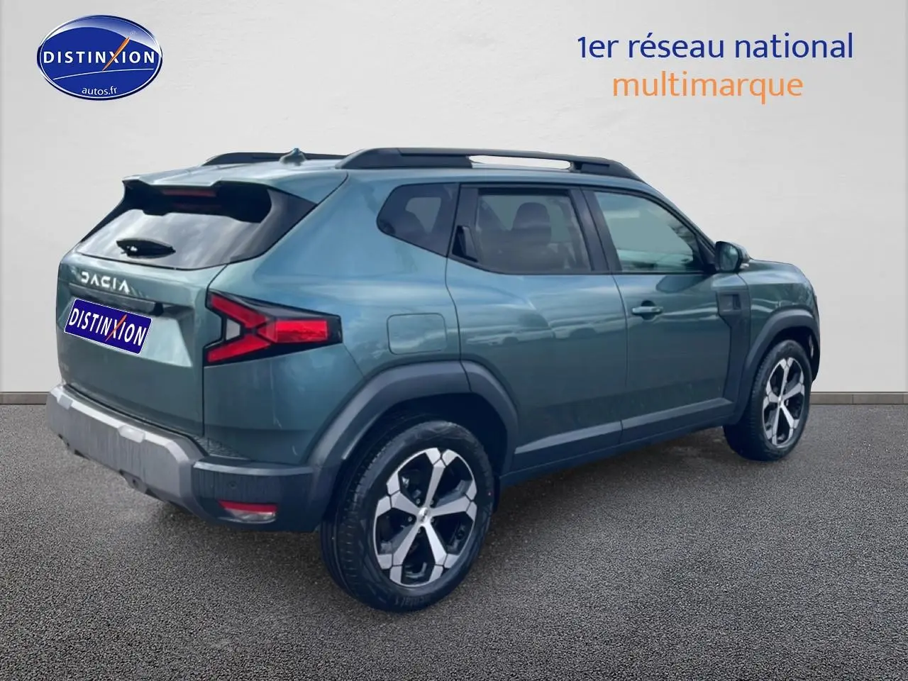 Vue 3/4 arrière droite du Dacia Duster 2026 vert cèdre avec jantes alu et barres de toit noires.