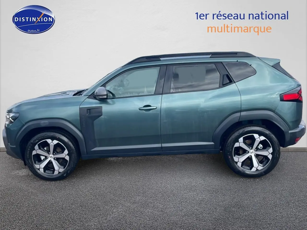 Profil droit du Dacia Duster 2026 vert cèdre avec jantes alu et barres de toit noires.