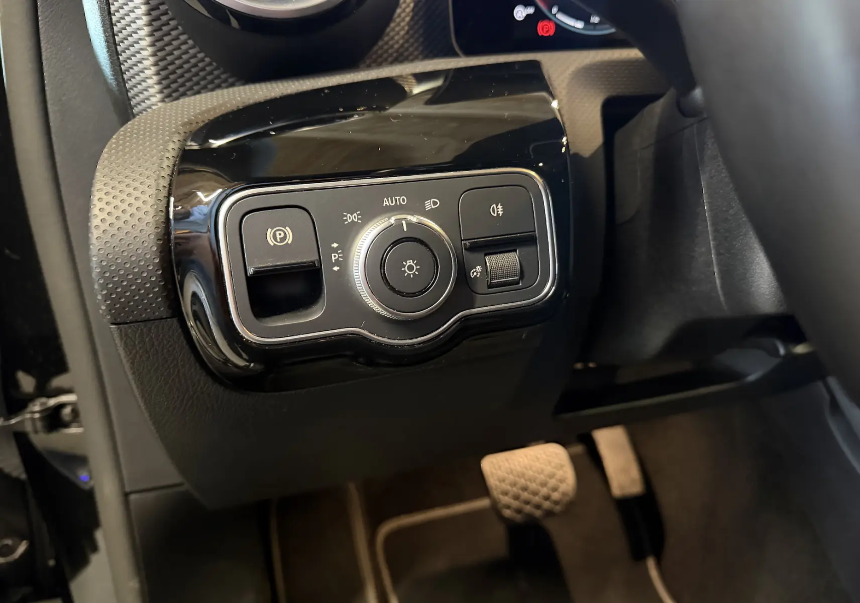 Gros plan sur le panneau de commande des phares et frein à main électrique dans l'habitacle noir d'une Mercedes Classe A 2022.