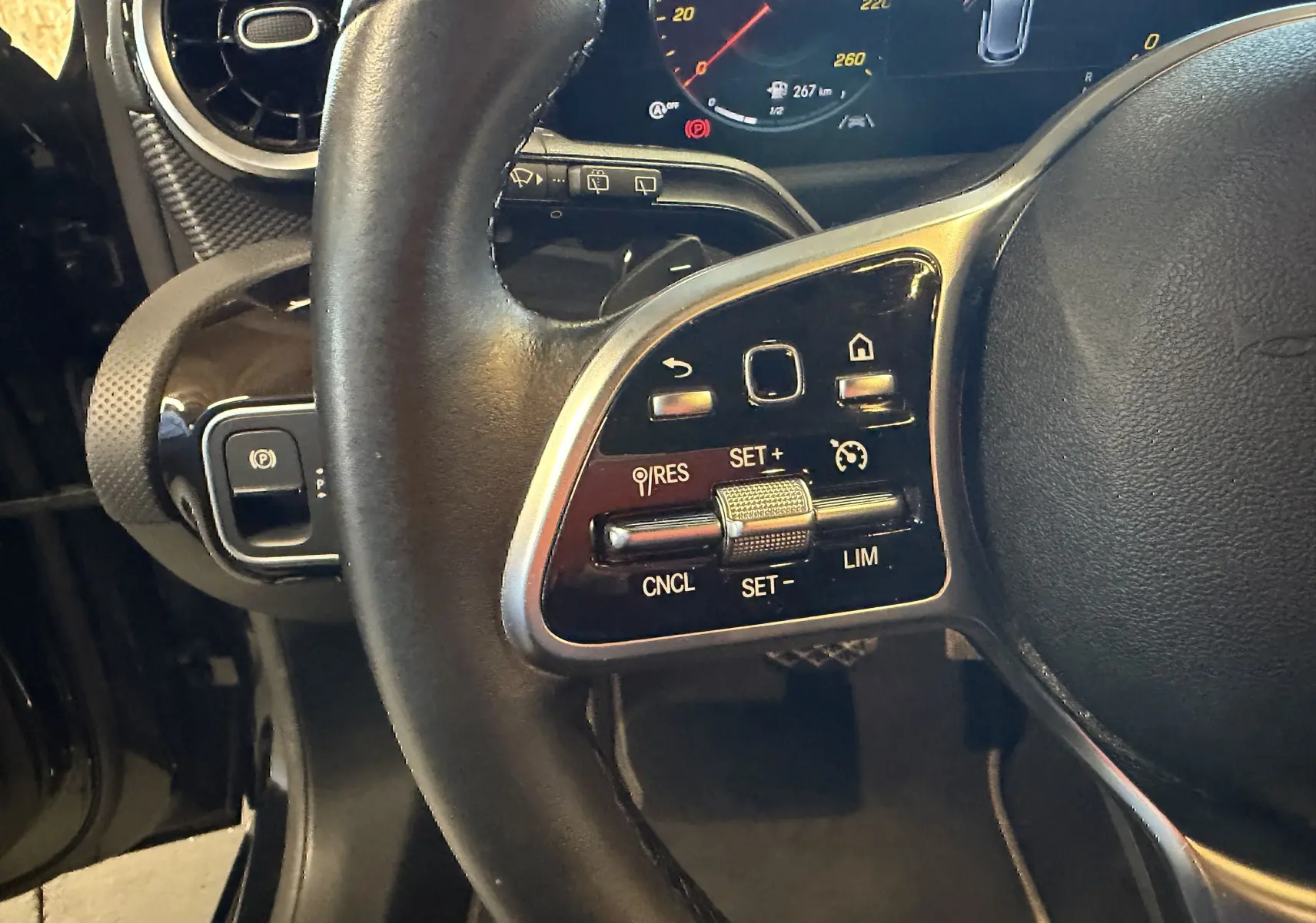 Gros plan sur le volant cuir multifonctions noir de la Mercedes Classe A 2022, avec commandes de régulateur de vitesse.