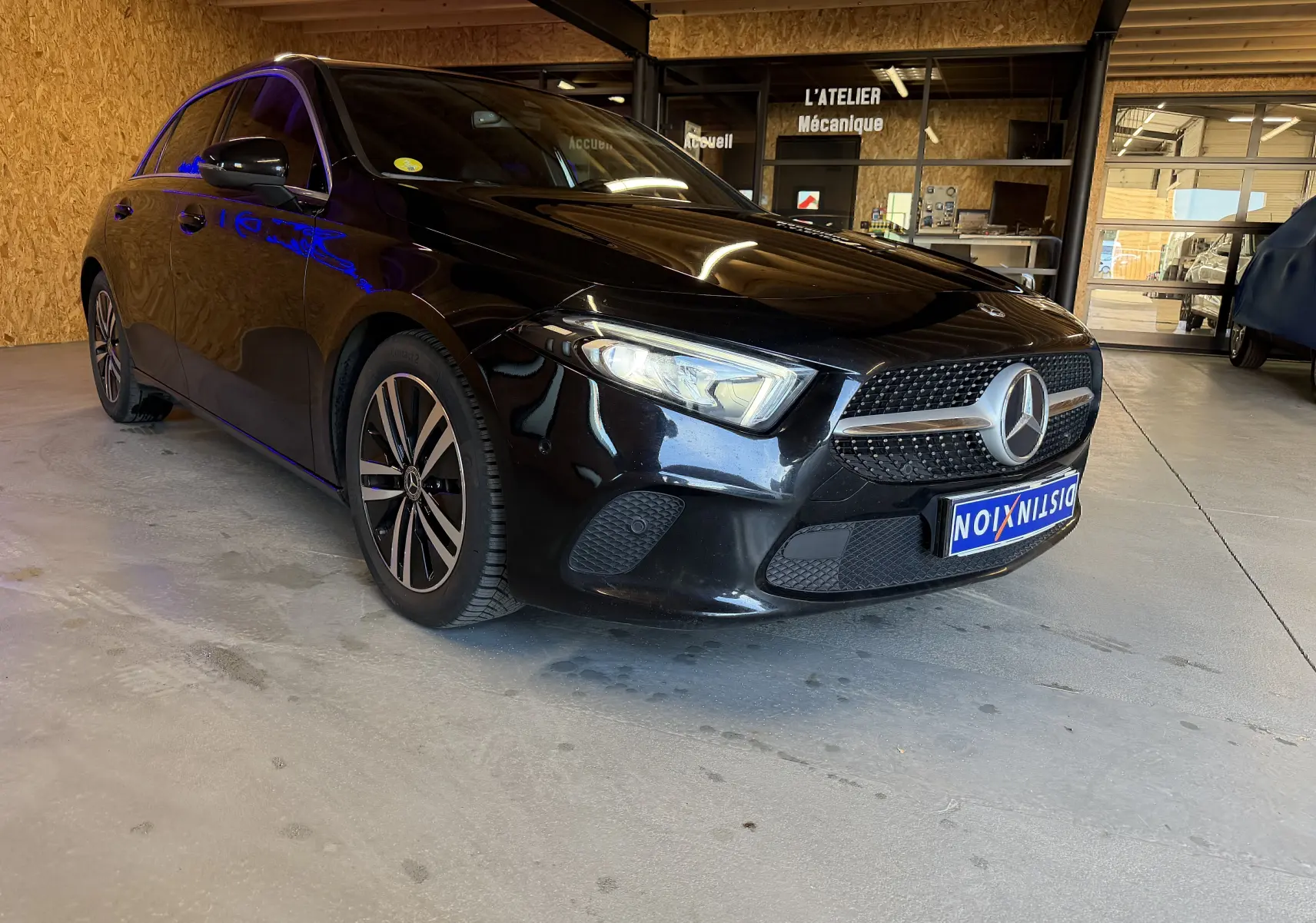 Mercedes Classe A noire vue en 3/4 avant droit dans un garage avec jantes alliage et calandre étoilée chromée.