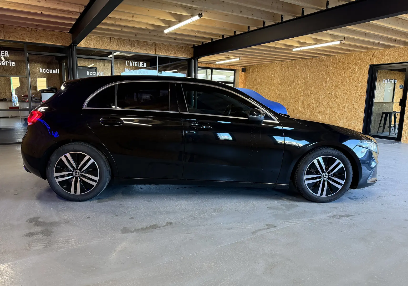 Profil droit d'une Mercedes Classe A noire 2022 avec jantes alliage et vitres teintées dans un garage.